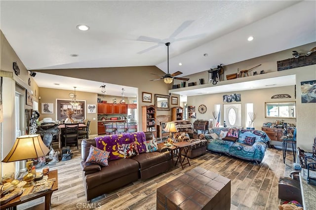 living room featuring vaulted ceiling and ceiling fan with notable chandelier