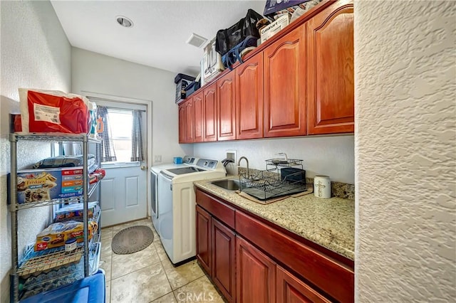 washroom with washing machine and dryer, cabinets, light tile patterned flooring, and sink