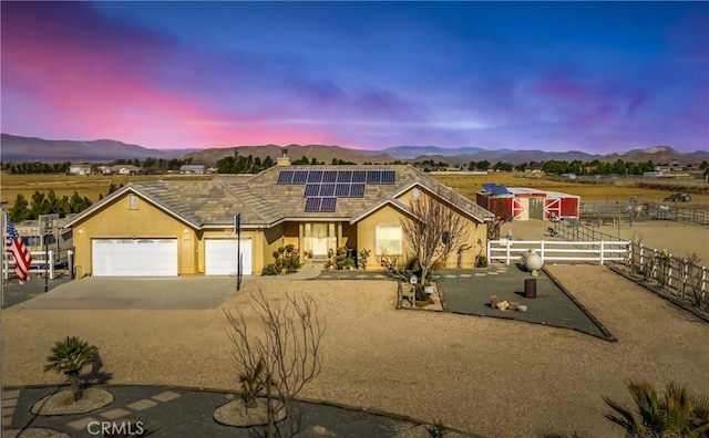 view of front of property with a mountain view, solar panels, and a garage