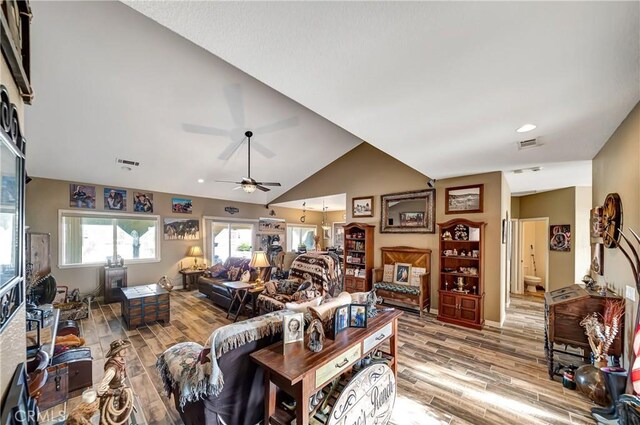 living room featuring light hardwood / wood-style floors, ceiling fan, and vaulted ceiling