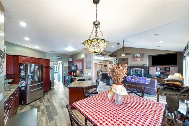 dining room with vaulted ceiling, sink, ceiling fan with notable chandelier, and hardwood / wood-style flooring