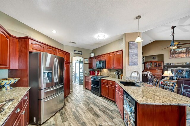 kitchen featuring pendant lighting, black appliances, sink, light stone counters, and light hardwood / wood-style flooring