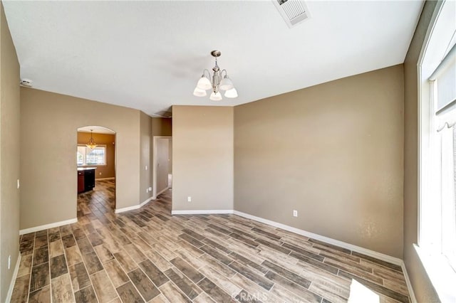 7315 W W Ave A8, Lancaster, CA 93536 - empty room featuring a chandelier, arched walkways, baseboards, and wood finished floors
