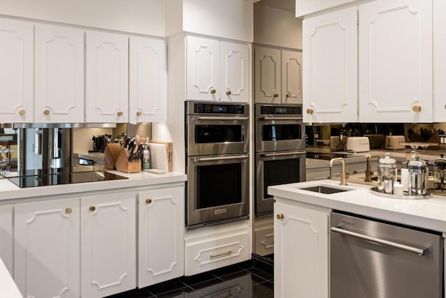 kitchen with dark tile patterned flooring, appliances with stainless steel finishes, sink, and white cabinetry