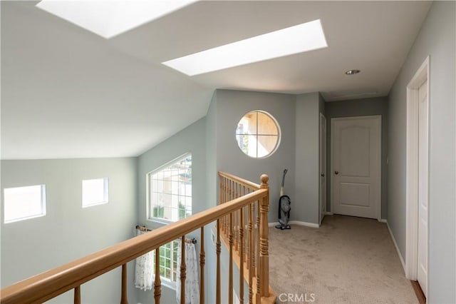 hallway featuring light carpet and lofted ceiling with skylight