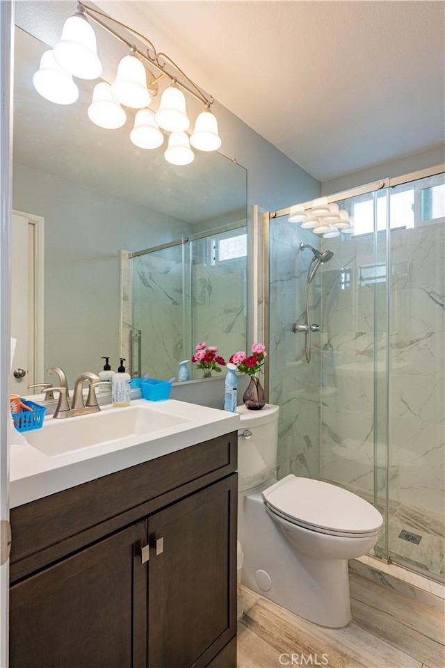 bathroom featuring hardwood / wood-style flooring, an enclosed shower, vanity, and toilet