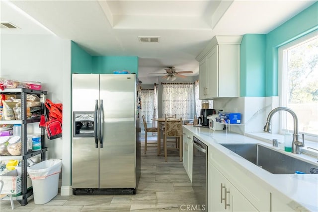 kitchen featuring ceiling fan, appliances with stainless steel finishes, white cabinets, and sink