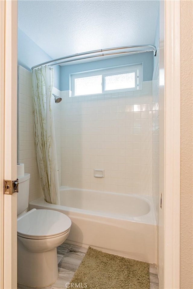 bathroom featuring toilet and shower / tub combo with curtain