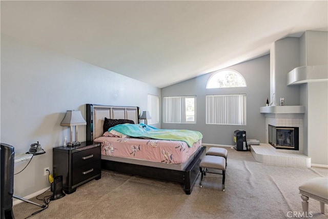 bedroom featuring light colored carpet, vaulted ceiling, and a fireplace