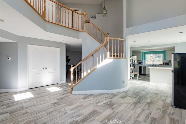 staircase featuring a towering ceiling and wood-type flooring