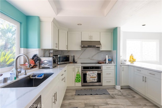 kitchen featuring decorative backsplash, sink, appliances with stainless steel finishes, white cabinets, and light stone counters