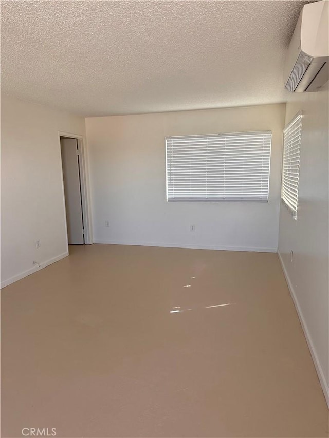 empty room featuring a textured ceiling and a wall mounted air conditioner