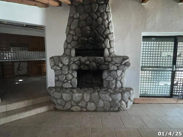 unfurnished living room featuring light tile patterned floors, a stone fireplace, and beamed ceiling