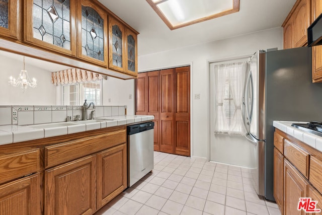 kitchen with dishwasher, light tile patterned flooring, a chandelier, and tile counters