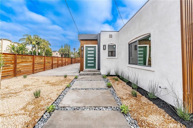 property entrance with fence and stucco siding