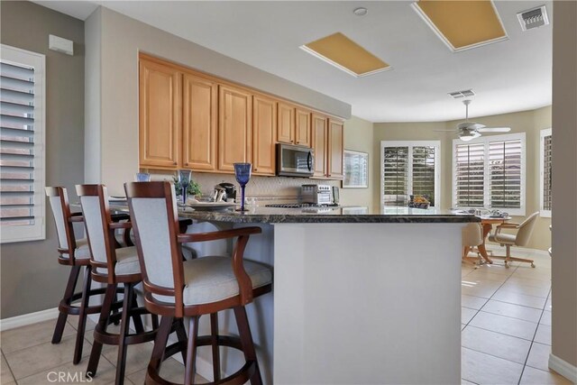 kitchen featuring ceiling fan, tasteful backsplash, kitchen peninsula, and light tile patterned flooring