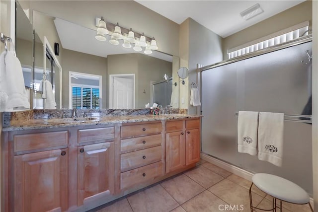 bathroom with a shower with shower door, vanity, and tile patterned floors