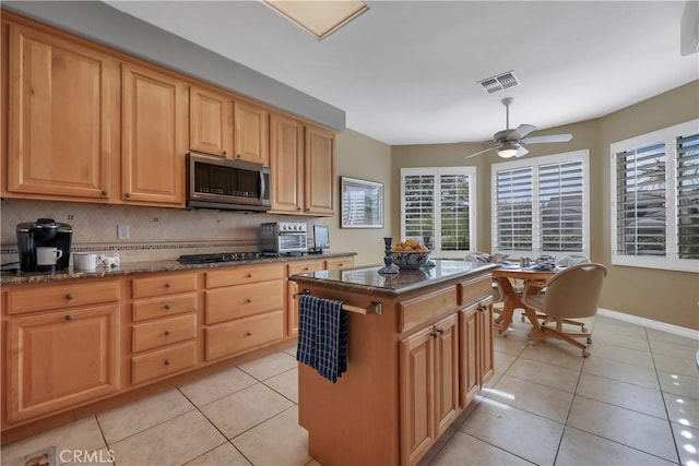 kitchen featuring tasteful backsplash, ceiling fan, black gas stovetop, a kitchen island, and light tile patterned floors