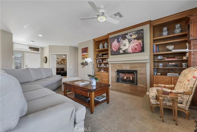 carpeted living room featuring ceiling fan, built in features, and a fireplace