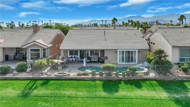 rear view of property featuring a fenced in pool, a patio area, a mountain view, and a yard