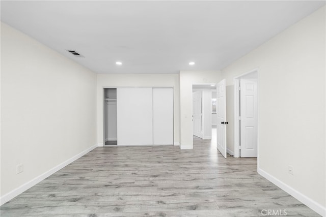 unfurnished bedroom with a closet and light wood-type flooring