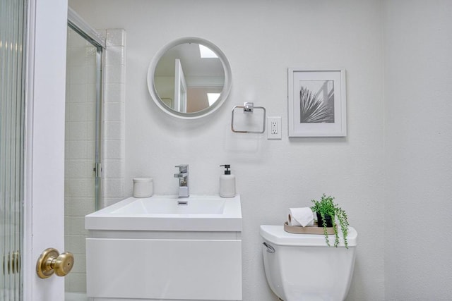 bathroom with vanity, toilet, and a shower with door