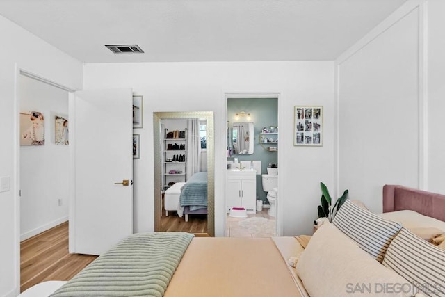 bedroom featuring light hardwood / wood-style floors, sink, and ensuite bath