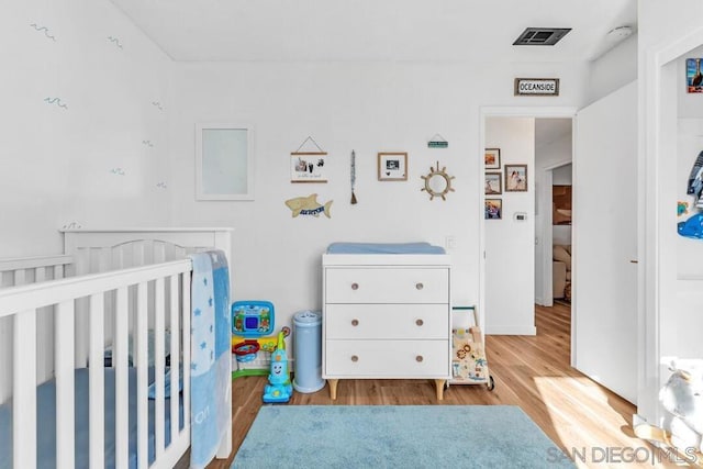 bedroom with a crib and light wood-type flooring