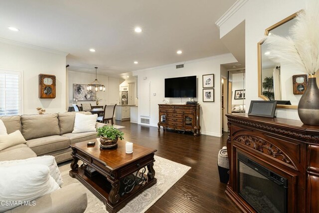 living room featuring dark hardwood / wood-style flooring, an inviting chandelier, and ornamental molding