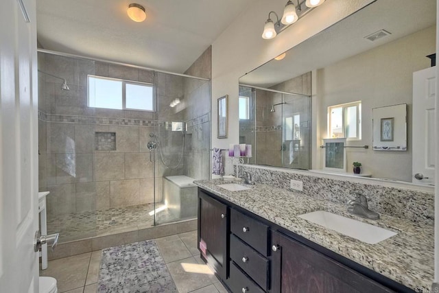 bathroom with a shower with door, vanity, tile patterned floors, and toilet