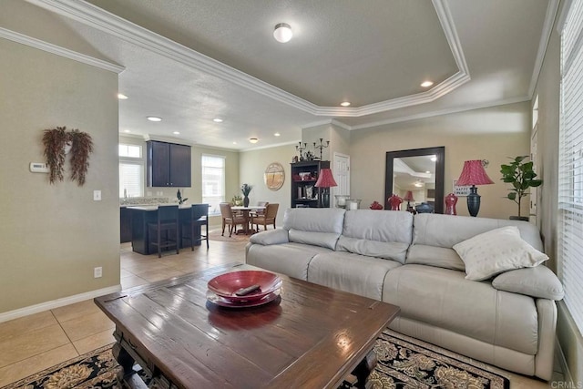 living room with crown molding, a raised ceiling, and light tile patterned floors