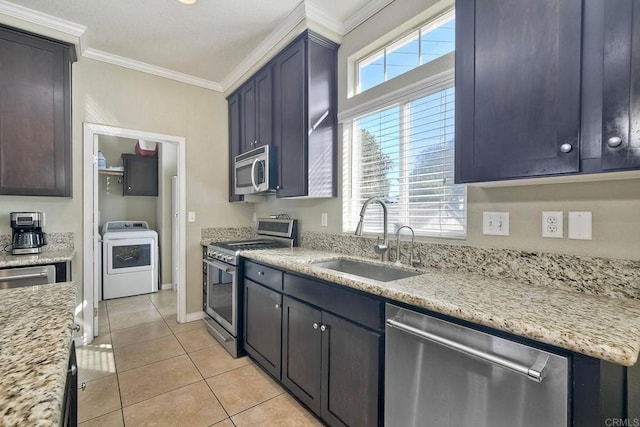 kitchen featuring light tile patterned flooring, washer / dryer, sink, ornamental molding, and stainless steel appliances