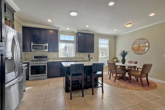 kitchen with stainless steel appliances, crown molding, light tile patterned floors, and a kitchen bar