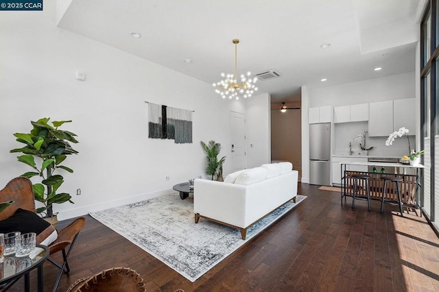 living room featuring dark wood-type flooring and ceiling fan with notable chandelier