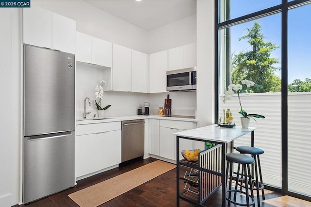 kitchen with dark hardwood / wood-style flooring, sink, stainless steel appliances, and white cabinetry