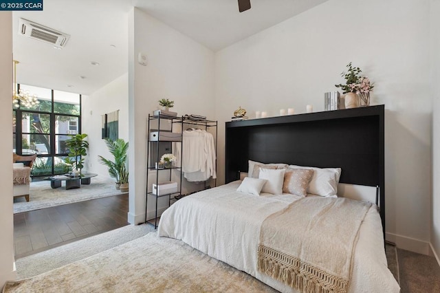 bedroom featuring hardwood / wood-style flooring, expansive windows, and ceiling fan