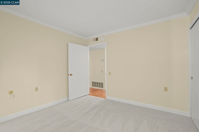 spare room with ornamental molding and light colored carpet