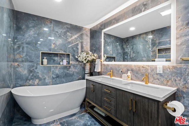 bathroom featuring a tub, vanity, and tile walls