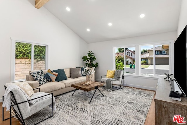 living room featuring light wood-type flooring, a wealth of natural light, high vaulted ceiling, and beamed ceiling