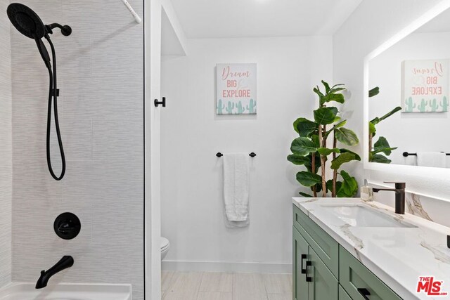 bathroom with toilet, vanity, and a tile shower