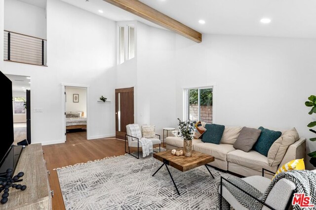 living room featuring light hardwood / wood-style floors, beam ceiling, and high vaulted ceiling