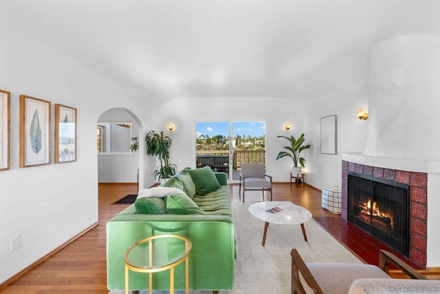 living room with a tiled fireplace and wood-type flooring