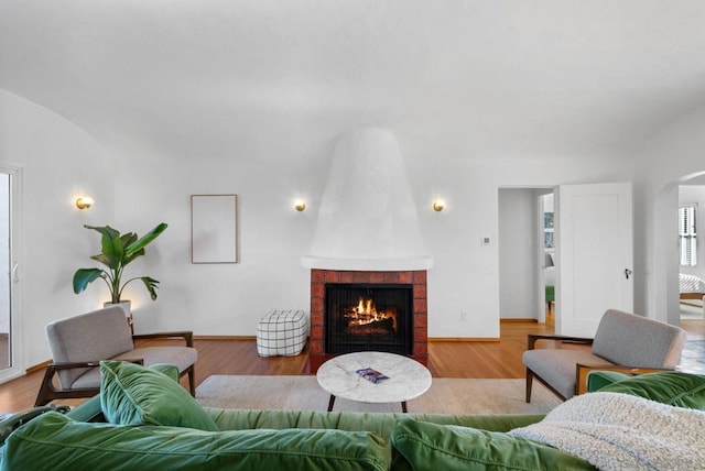 living room featuring light wood-type flooring, vaulted ceiling, and a tile fireplace