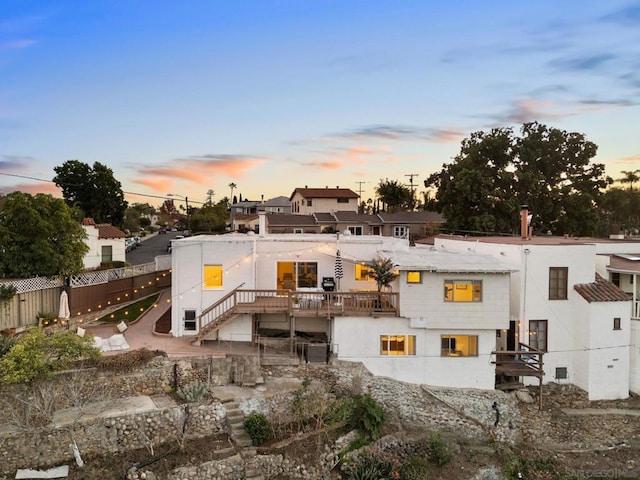 back house at dusk featuring a deck