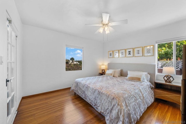 bedroom with ceiling fan, multiple windows, and wood-type flooring