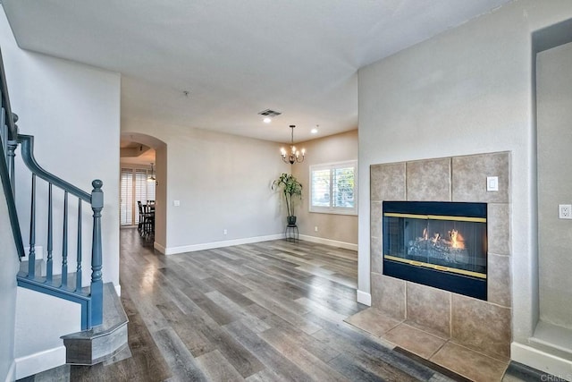 unfurnished living room with hardwood / wood-style flooring, a chandelier, and a fireplace