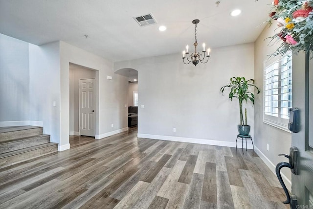 unfurnished room featuring an inviting chandelier and wood-type flooring