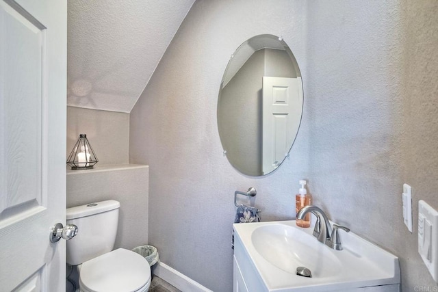 bathroom featuring lofted ceiling, toilet, a textured ceiling, and vanity