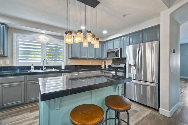 kitchen featuring sink, decorative light fixtures, a center island, dark hardwood / wood-style floors, and stainless steel appliances