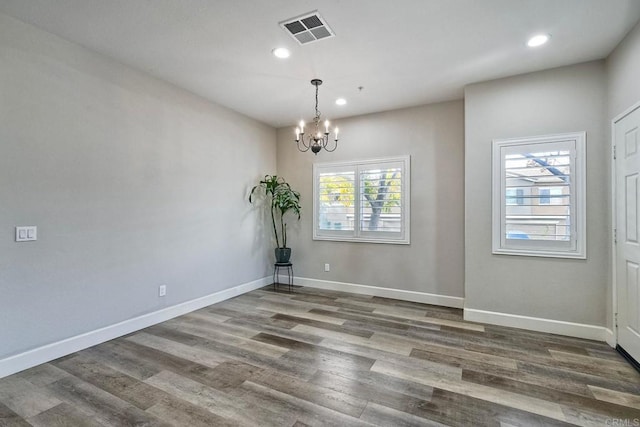 spare room featuring hardwood / wood-style flooring and a chandelier